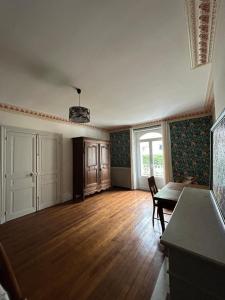 an empty living room with a table and a window at La Maison des Chanoines in Verdun-sur-Meuse