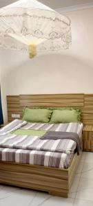 sypialnia z drewnianym łóżkiem z zielonymi poduszkami w obiekcie VENUS APARTMENT Kigali w mieście Kigali