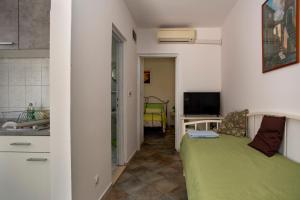 Sala de estar con cama verde y TV en Apartments Ina & Ika, en Rovinj