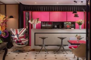 uma cozinha com armários cor-de-rosa, uma mesa e cadeiras em NH Paris Opéra Faubourg em Paris