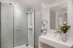 uma casa de banho com um chuveiro, um lavatório e um espelho. em NH Paris Champs-Elysées em Paris