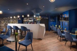 un ristorante con pareti e sedie blu e un bar di NH Paris Champs-Elysées a Parigi