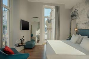a bedroom with a large bed and a chair at NH Collection Roma Fori Imperiali in Rome