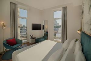 a bedroom with a large bed and a room with windows at NH Collection Roma Fori Imperiali in Rome