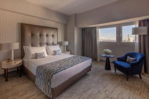 a bedroom with a large bed and a blue chair at Tivoli Oriente Lisboa Hotel in Lisbon