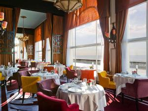- une salle à manger avec des tables, des chaises et des fenêtres dans l'établissement Le Grand Hotel de Cabourg - MGallery Hotel Collection, à Cabourg