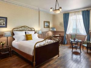 a hotel room with a bed and a desk at Le Grand Hotel de Cabourg - MGallery Collection in Cabourg