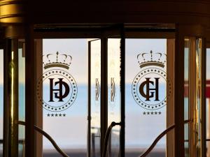 Le Grand Hotel de Cabourg - MGallery Hotel Collection في كابورغ: باب زجاجي عليه شعار تاج