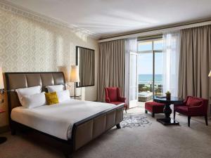 a hotel room with a bed and a large window at Le Grand Hotel de Cabourg - MGallery Collection in Cabourg