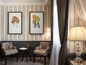 a hotel room with two chairs and paintings on the wall at Le Grand Hotel de Cabourg - MGallery Collection in Cabourg