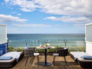 a balcony with a table and chairs and the ocean at Le Grand Hotel de Cabourg - MGallery Collection in Cabourg