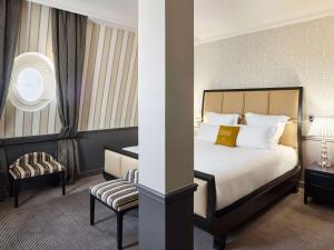 a hotel room with a bed and a chair at Le Grand Hotel de Cabourg - MGallery Collection in Cabourg