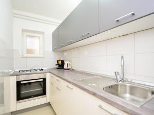 a kitchen with white cabinets and a stainless steel sink at Apartment Miro-1 by Interhome in Grebaštica