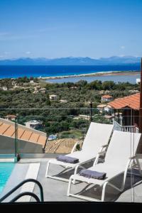 een zwembad met 2 ligstoelen en het water bij Dom in Lefkada