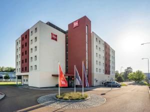 Ibis Hotel Plzeň في بلزن: مبنى الفندق مع وجود اعلام امامه