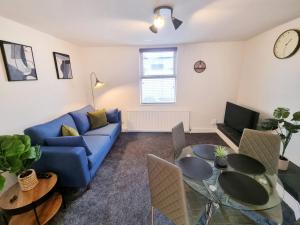 uma sala de estar com um sofá azul e uma mesa em COSY 2 Bed APARTMENT NEARBY TRAIN STATION! em Watford