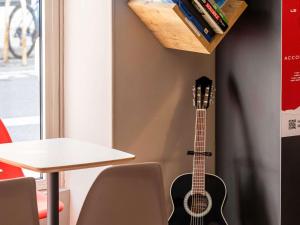 una guitarra colgada en una pared junto a una mesa en ibis Nice Centre Notre Dame, en Niza
