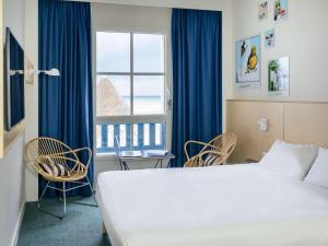 a hotel room with a bed and chairs and a window at ibis Styles Deauville Villers Plage in Villers-sur-Mer