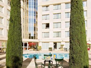 a pool in front of a building with a table and chairs at Novotel Suites Montpellier Antigone in Montpellier