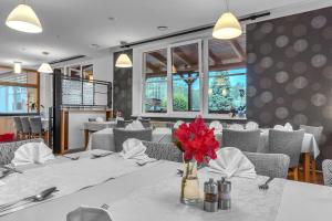 a dining room with a table with red flowers in a vase at Hotel Za Vodou in Dvůr Králové nad Labem