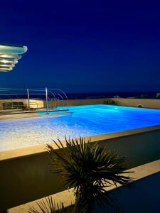 Erbavoglio Hotel في ريميني: حمام سباحة كبير في الليل مع أضواء زرقاء