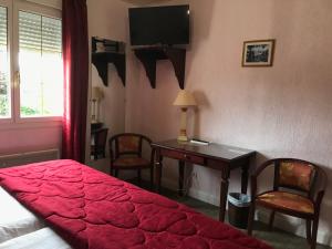 een slaapkamer met een bed en een bureau met een televisie bij Logis Hôtel & Restaurant - Le Château Des Tourelles in Le Wast