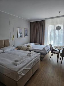 a hotel room with two beds and a table at Apartamenty Piekarczyk - Elbląg in Elblag