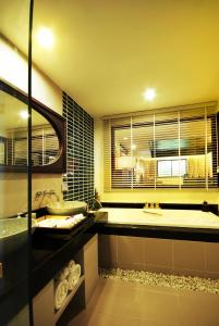 een badkamer met een bad, een wastafel en een bad bij Khaolak Orchid Beach Resort - SHA Extra Plus in Khao Lak