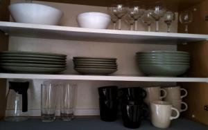 a shelf with plates and cups and wine glasses at Spacious & cleаn 4 isolated rooms best for groups in Bratislava