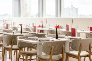 - une salle à manger avec des tables, des chaises et des fenêtres dans l'établissement NH Collection Brussels Centre, à Bruxelles