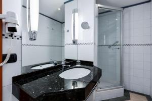 La salle de bains est pourvue d'un lavabo et d'une douche. dans l'établissement NH Collection Brussels Centre, à Bruxelles