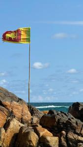 a flag on top of some rocks near the ocean at Olive Launch in Weligama