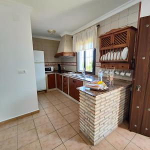 a kitchen with wooden cabinets and a counter top at Chalet de dos plantas con jardín, solo familias y parejas in Hozanejos +8 photos
