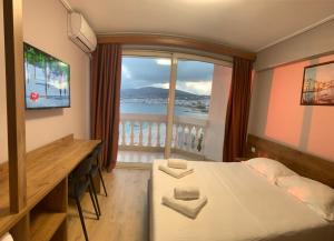 薩蘭達的住宿－多多納酒店，一间卧室配有一张床、一张书桌和一个窗户。