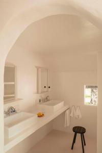 - une salle de bains blanche avec deux lavabos et un tabouret dans l'établissement Les Bains Gardians, à Saintes-Maries-de-la-Mer
