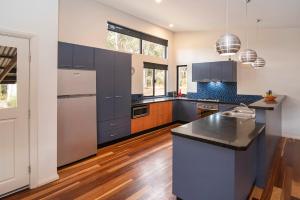 una cocina con armarios azules y electrodomésticos de acero inoxidable en Cape Illawarra Holiday House Margaret River, en Margaret River Town