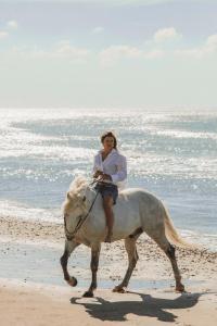 une femme faisant de l'équitation sur la plage dans l'établissement Les Bains Gardians, à Saintes-Maries-de-la-Mer