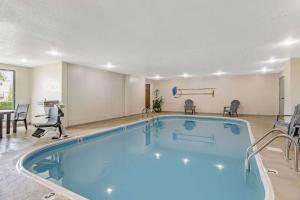 una piscina en una habitación de hotel con sillas alrededor en Comfort Suites near I-80 and I-94, en Lansing