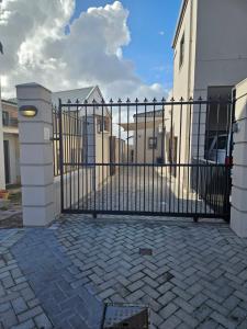 un cancello nero in ferro battuto con un vialetto di mattoni di Suburban Bliss Durbanville a Kraaifontein