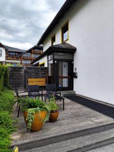 una terraza de madera con 2 bancos y 2 macetas en Haus Katris, en Mauterndorf