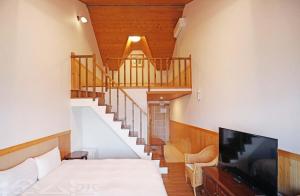 仁愛鄉的住宿－清境 百里莊園 Baili Manor Cing Jing，一间带床和电视的房间以及楼梯