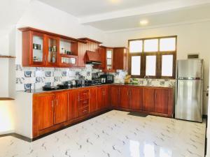 a kitchen with wooden cabinets and a stainless steel refrigerator at Villa365 in Godagama