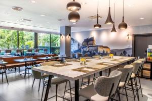 NH Luxembourg في لوكسمبورغ: غرفة طعام مع طاولة وكراسي طويلة