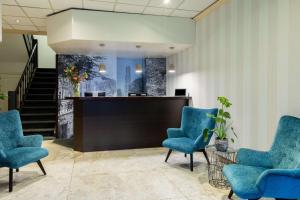 a lobby with blue chairs and a reception desk at NH Centre Utrecht Hotel in Utrecht