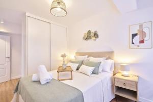 a white bedroom with a large bed and a table at El Balcón de Jauregui centro in Salamanca