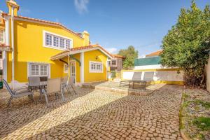 a yellow house with chairs and a table in front of it at GuestReady - Traditional home in Parede in Parede