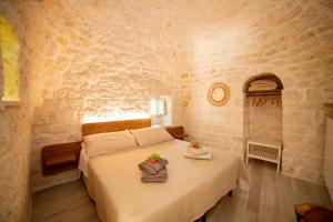 1 dormitorio con 1 cama en una pared de piedra en Trulli Balè en Locorotondo