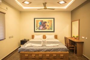 1 dormitorio con 1 cama y una pintura en la pared en Queens Paradise Estate Resort, en Pondicherry