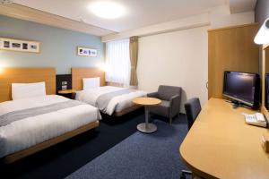 ein Hotelzimmer mit 2 Betten und einem Schreibtisch in der Unterkunft Comfort Hotel Saga in Saga