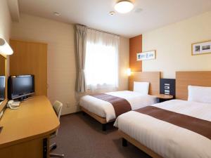 Habitación de hotel con 2 camas y escritorio con TV. en Comfort Hotel Tomakomai en Tomakomai
